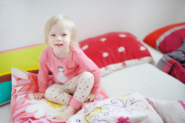 Little toddler girl in bed on sunny morning