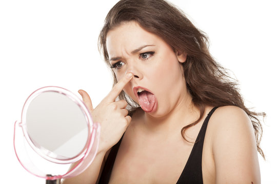 funny young woman in front of the mirror raises her nose