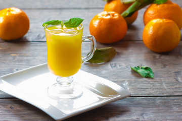 Mandarin  juice with leaf mint and ice cube on wooden background
