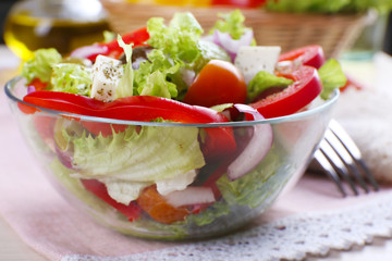 Greek salad in glass dish on napkin with fork, closeup