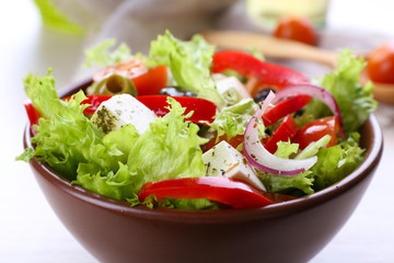 Greek salad in bow on wooden table background