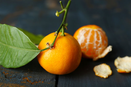 Juicy ripe tangerines with leaves on wooden table