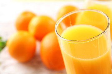 Glass of orange juice and oranges on wooden table background