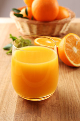 Glass of orange juice and wicker basket with oranges