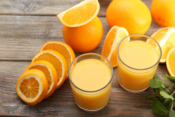 Glass of orange juice and slices on wooden table background