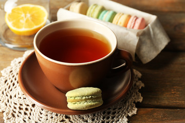 Colorful macaroons with cup of tea on wooden background