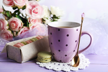 Colorful macaroons with cup of tea on wooden background