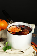 Old metal pan of tasty mulled wine on dark background