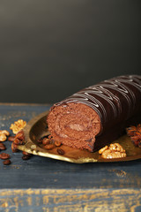 Delicious roll cake on wooden table, on dark background