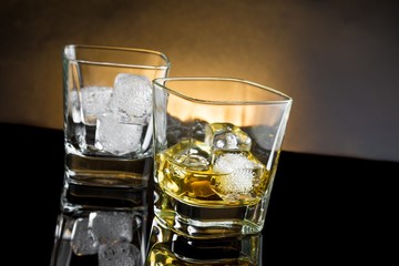 whiskey glasses with ice and warm light on black background