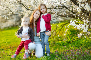 Fototapeta premium Young mother and her children in blooming garden