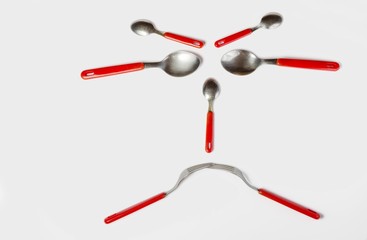frowning face made of spoons and forks