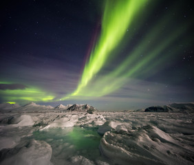 Fototapeta na wymiar Beautiful Northern Lights over the Arctic frozen fjord