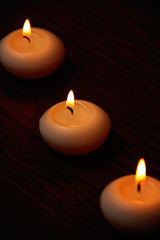 Obraz na płótnie Canvas Three candles on a dark wooden table.