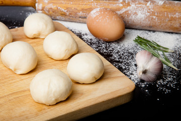 dough on a board with flour. olive oil, eggs, rolling pin, garli