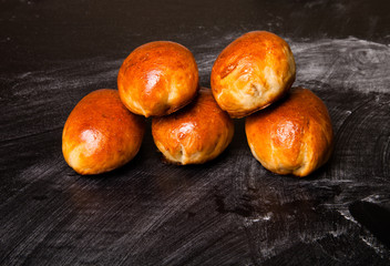 pies with meat or cabbage on a black background.