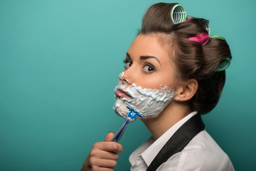 Cute brunette woman in hair curlers posing with foam on face sha