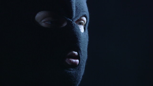 Anonymous person in black balaclava talking to camera