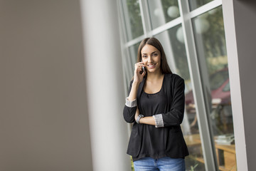 Young woman talking on the phone in front of office