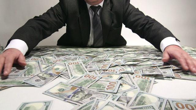 Greedy business person grabbing lot of hundred dollar bills