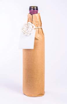 bottle wrapped in paper with white flower and card