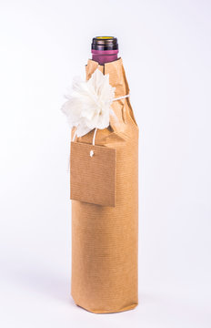bottle wrapped in paper with white flower and card