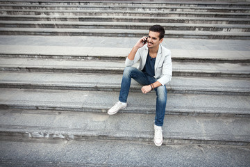 Fototapeta na wymiar Fashionable young man sitting on the stairs 