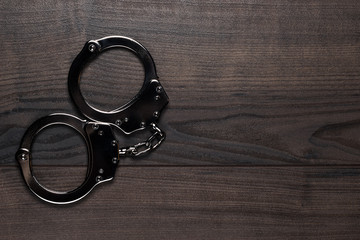 handcuffs on brown wooden table background