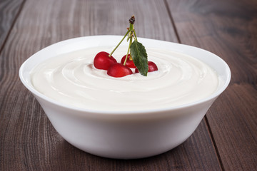 white bowl full of sour cream with some cherries