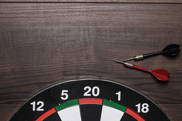 target and two darts on brown wooden table