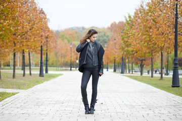 Fototapeta premium Happy woman in black coat walking autumn street