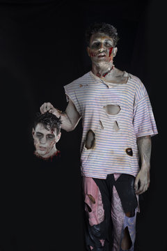 Scary male zombie holding another man's head