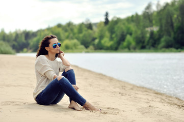 Young beautiful woman sitting near a beach