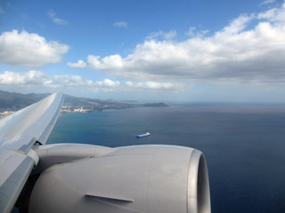 Aerial high in the sky shot of window view of plane leaving Hono