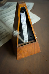 Naklejka premium Wooden metronome sets the rhythm by swinging pendulum