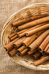 Cinnamon Sticks in a Srraw Basket on Linen Background