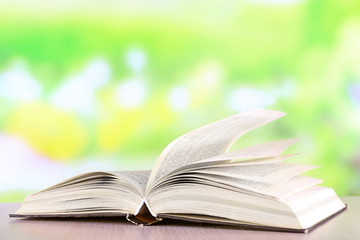 Open book on wooden table on natural background