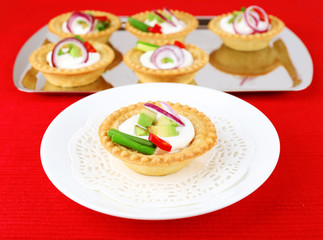 Tartlets with greens and vegetables with sauce on plate and