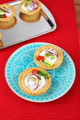 Tartlets with greens and vegetables with sauce on plate and