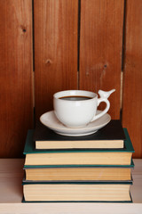 Fototapeta na wymiar Pile of books with cup on tabletop and wooden background