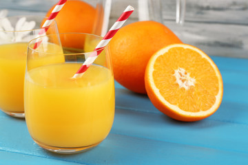 Glass of orange juice with slices, flowers and straws