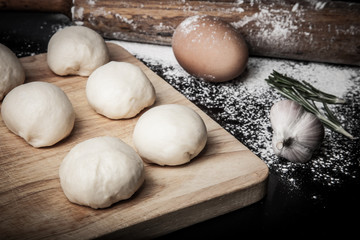 dough on a board with flour. olive oil, eggs, rolling pin, garli
