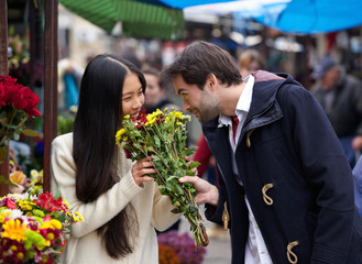Happy couple smelling flowers together
