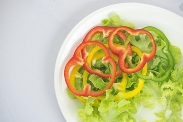 closed up of green oak lettuce with multi color bell peppers