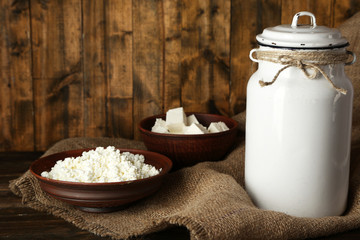 Milk can with cottage cheese on rustic wooden background