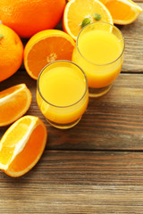 Glass of orange juice and slices on wooden table background