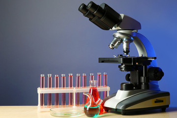 Microscope and test tubes on table, on color background