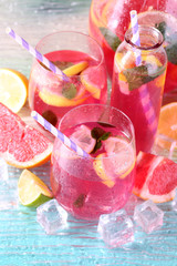 Pink lemonade in glasses and pitcher on bright background