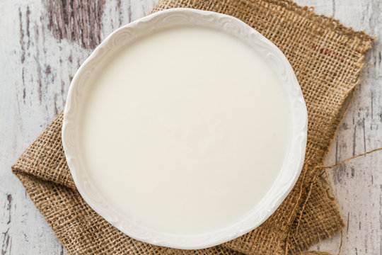 Plain Yogurt in white bowl on White Wooden Background
