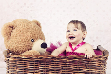 Beautiful little girl with big teddy bear in the wicker basket